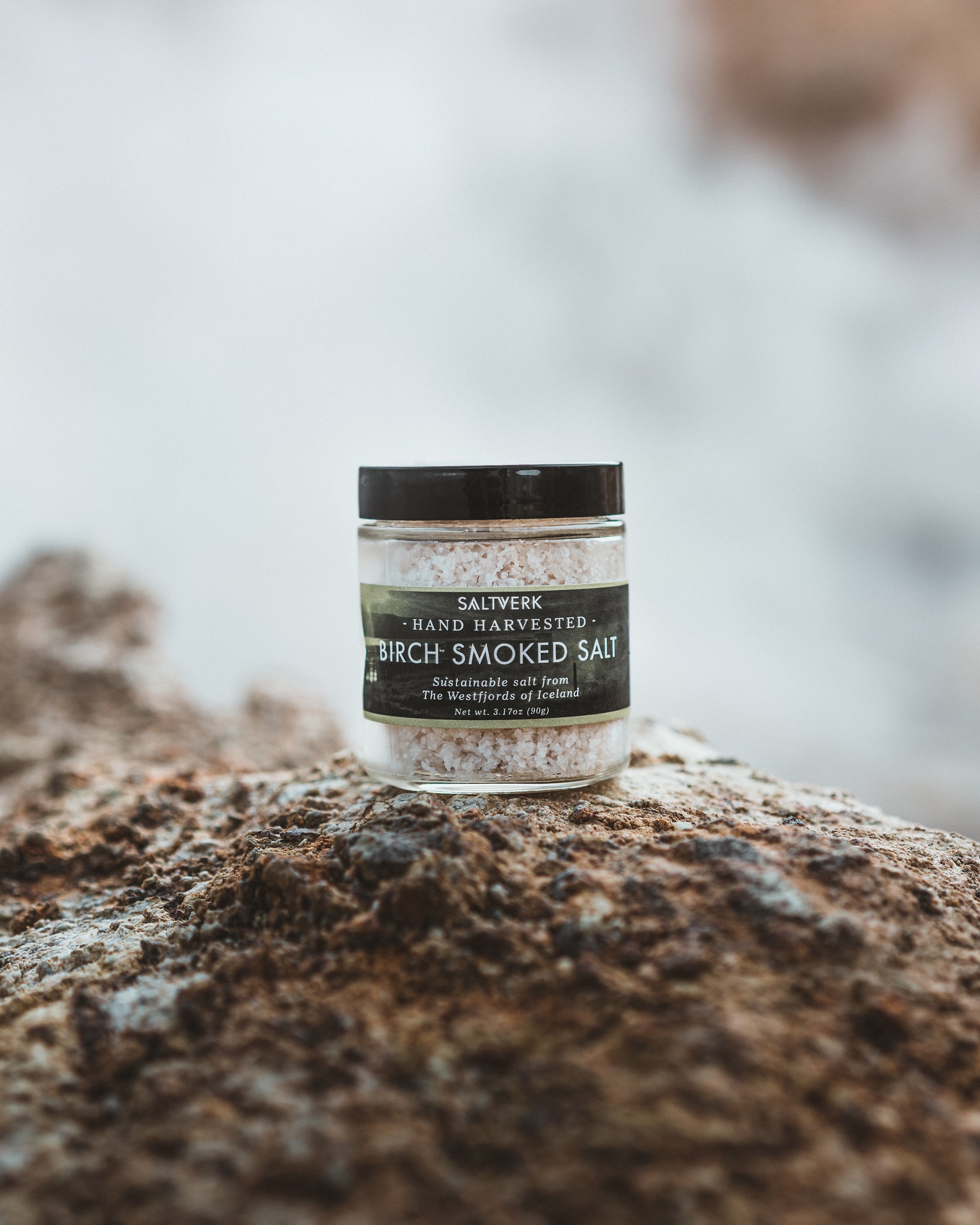 Jar of Salierwerk Birch Smoked Salt on a rock with a blurred natural background