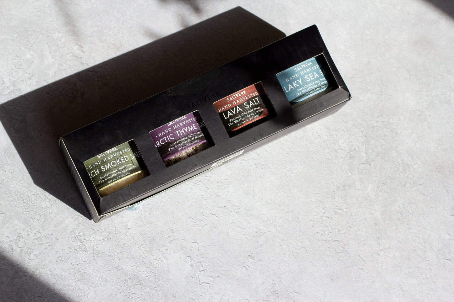 Set of three small containers with labels on a textured surface